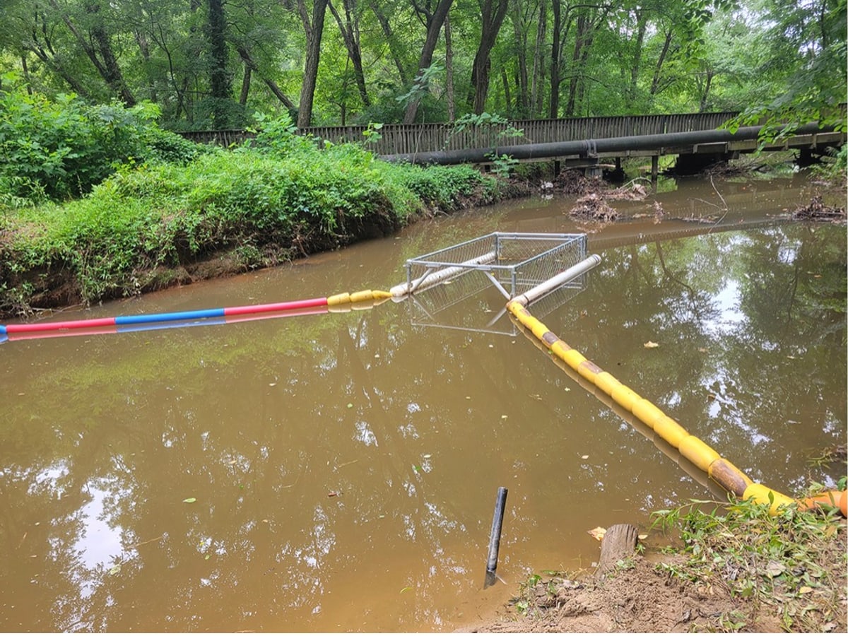 The Creek Guard floating in a river, with boom lines angled to funnel debris into the collection area.