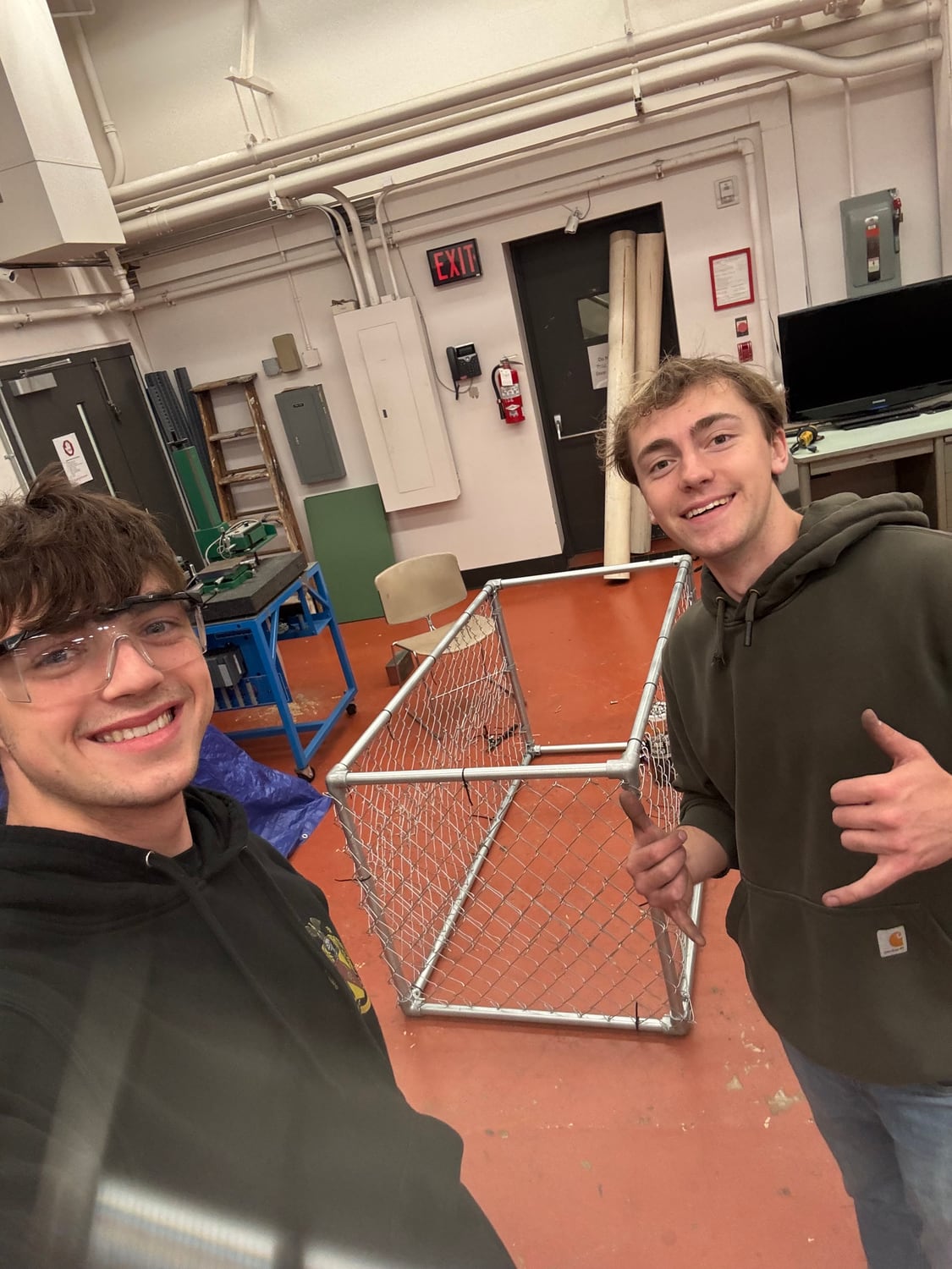 Max and Elliot standing either side of the finished Creek Guard frame in the workshop.